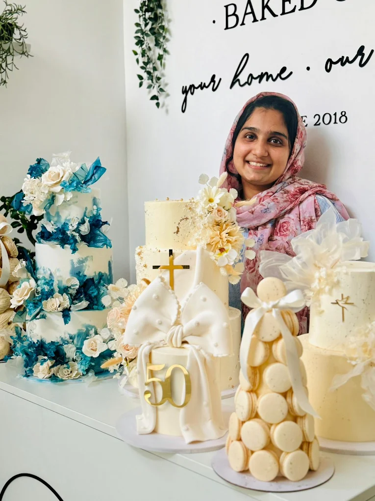 BakedOut founder smiling beside blue and ivory celebration cakes