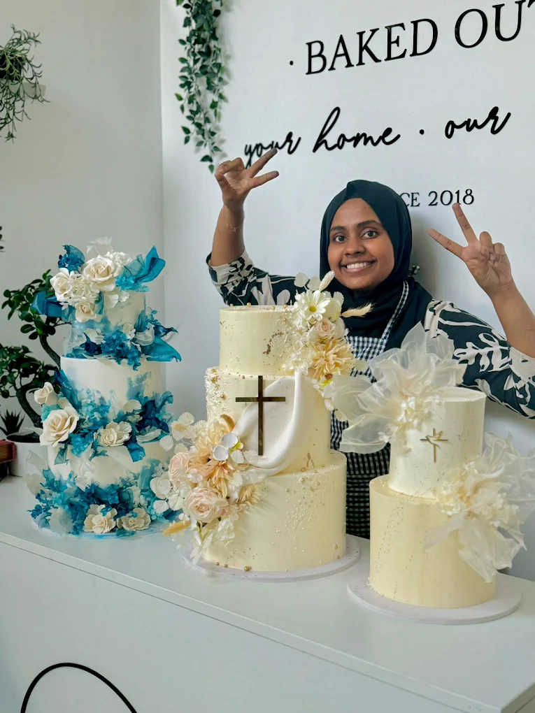 BakedOut team member posing beside premium celebration cakes